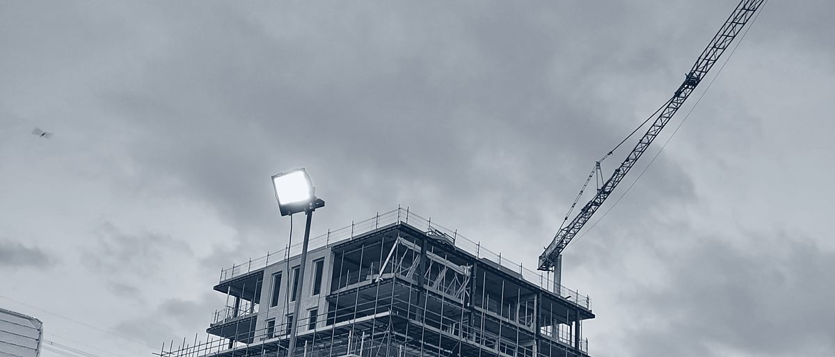 De campus van Husky in aanbouw bij schemer, met torenkraan boven de ruwbouw