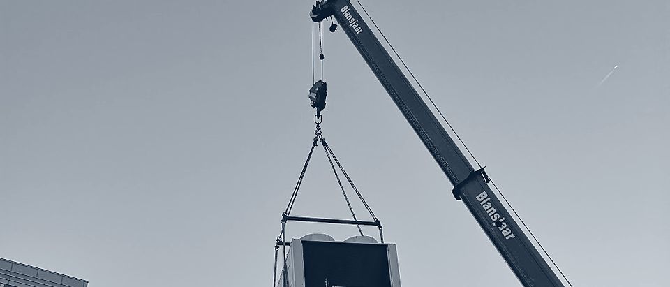 Een koelmachine hangt aan de kraan boven de stad